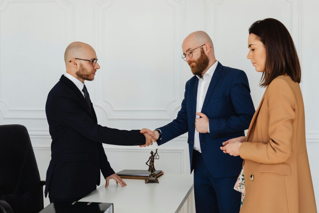 pexels photo 7875994 7875994 Three business professionals in formal attire shake hands during an office meeting.