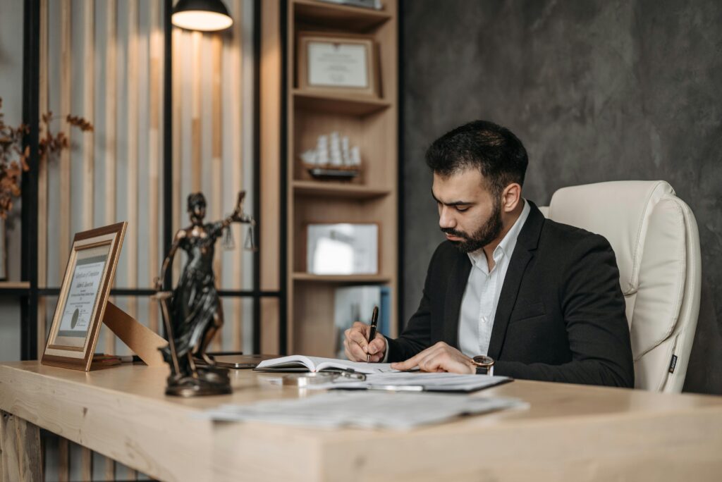pexels photo 8112113 8112113 A focused lawyer in an office setting writing and reviewing legal documents, symbolizing expertise and professionalism.